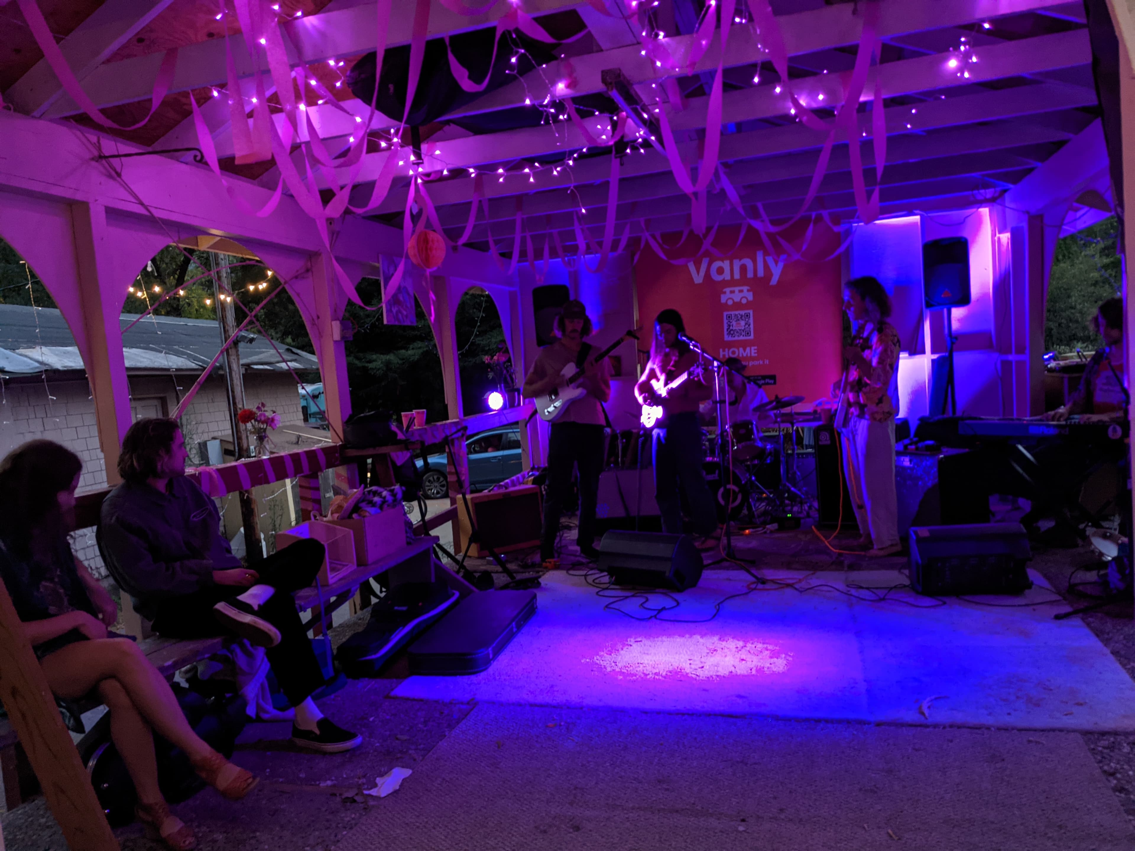 A band playing under string lights at the Vanly app launch party